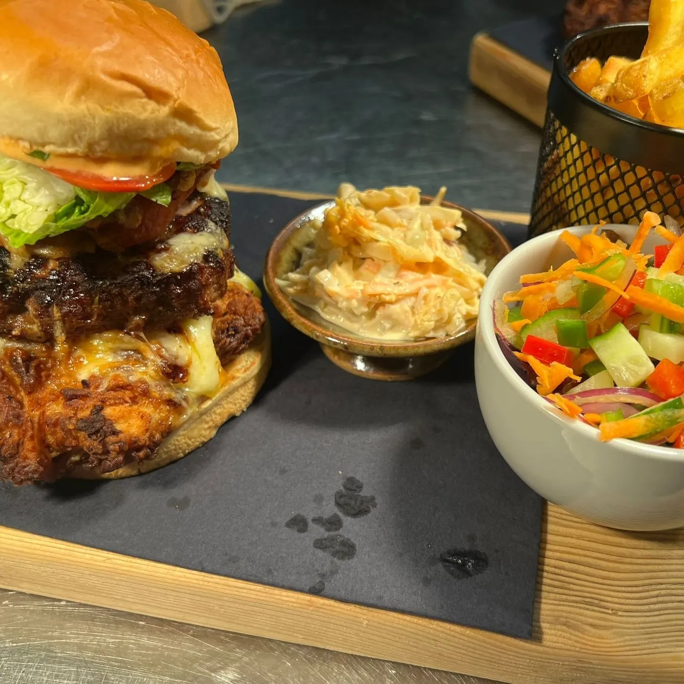 A burger with a bowl of salad and coleslaw.