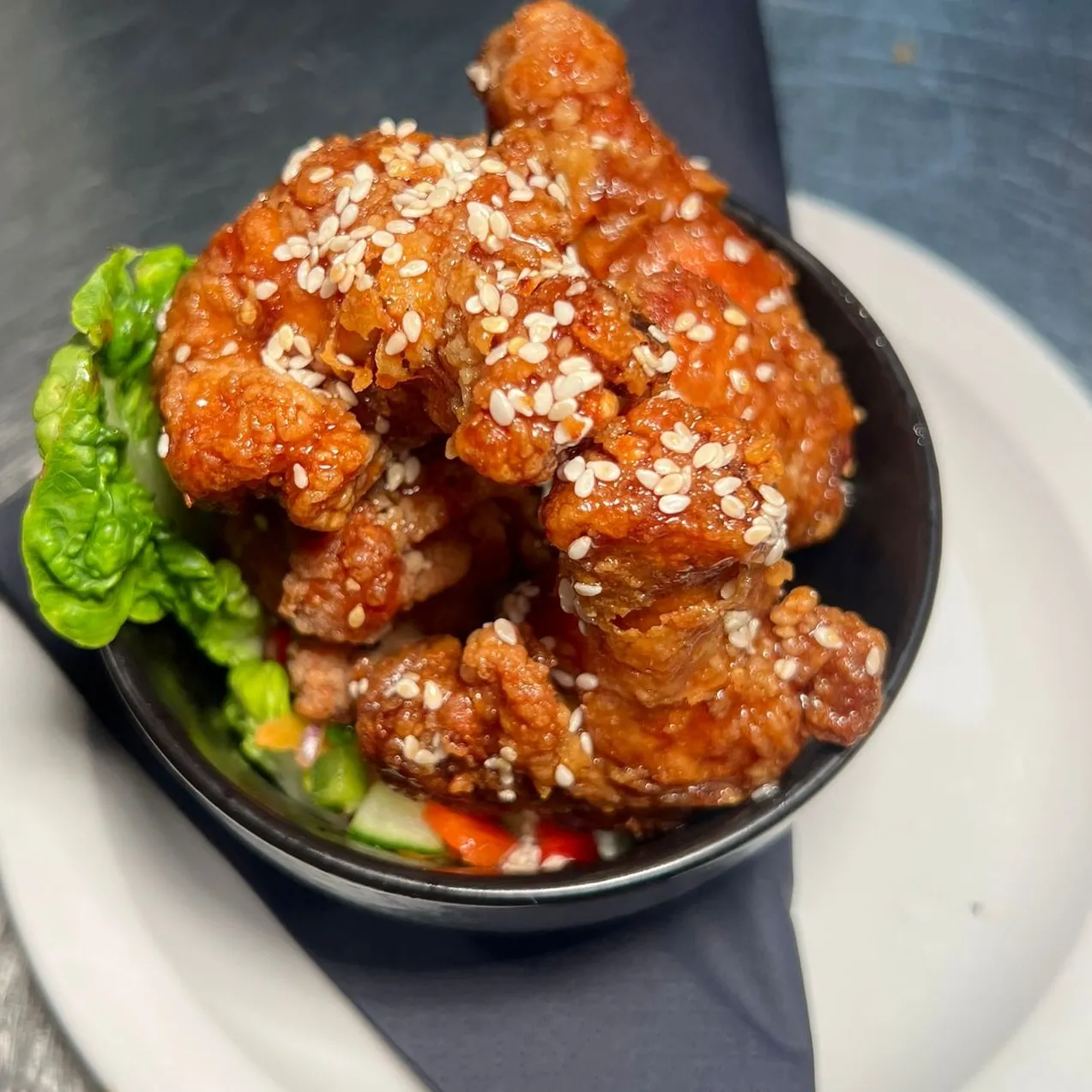 A bowl of spiced chicken on a bed of lettuce.