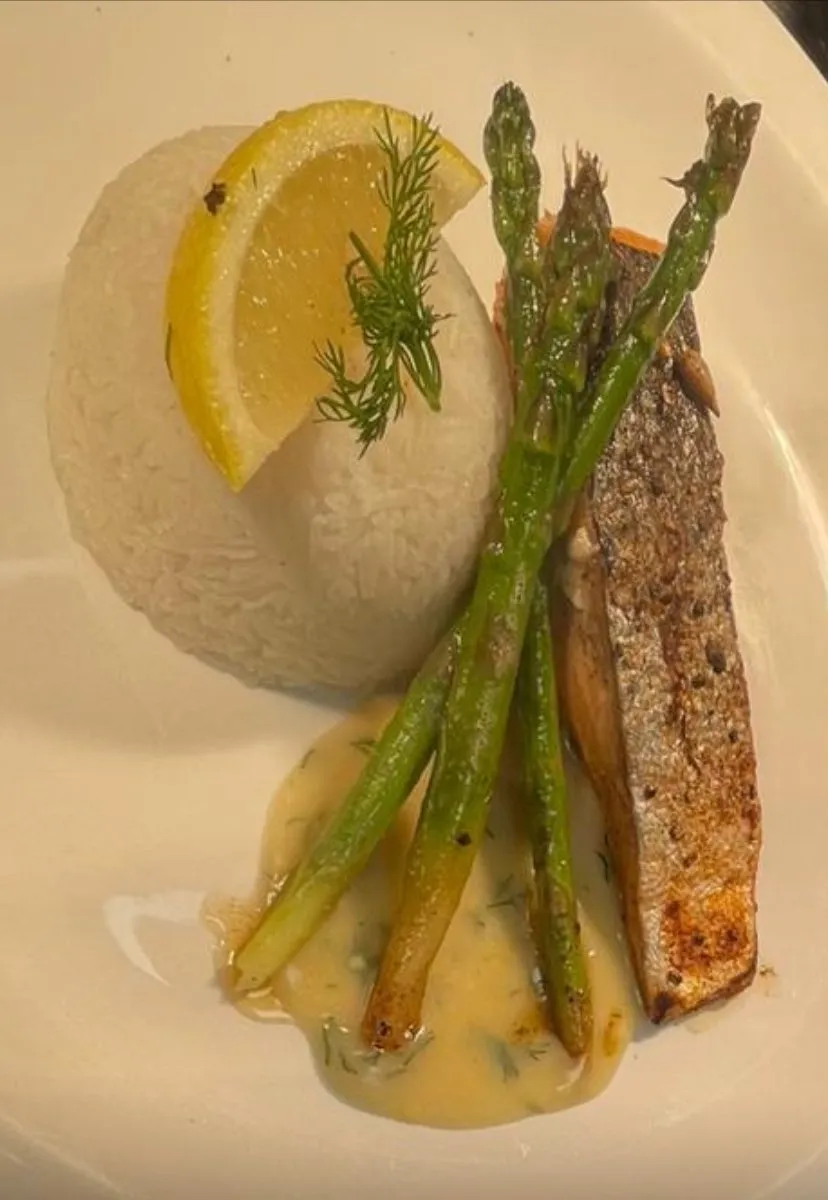 A white plate topped with fish, rice and asparagus.