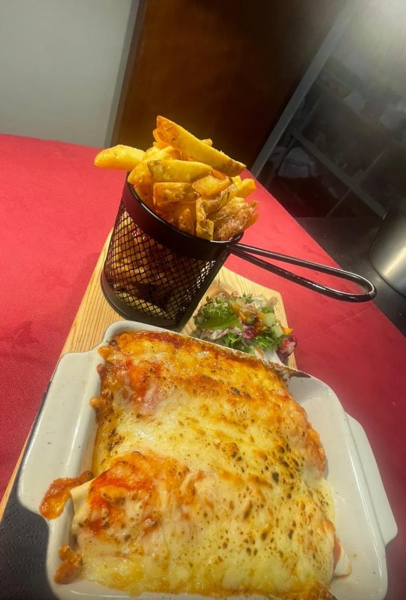 Fish pie and a basket of chips on a table.