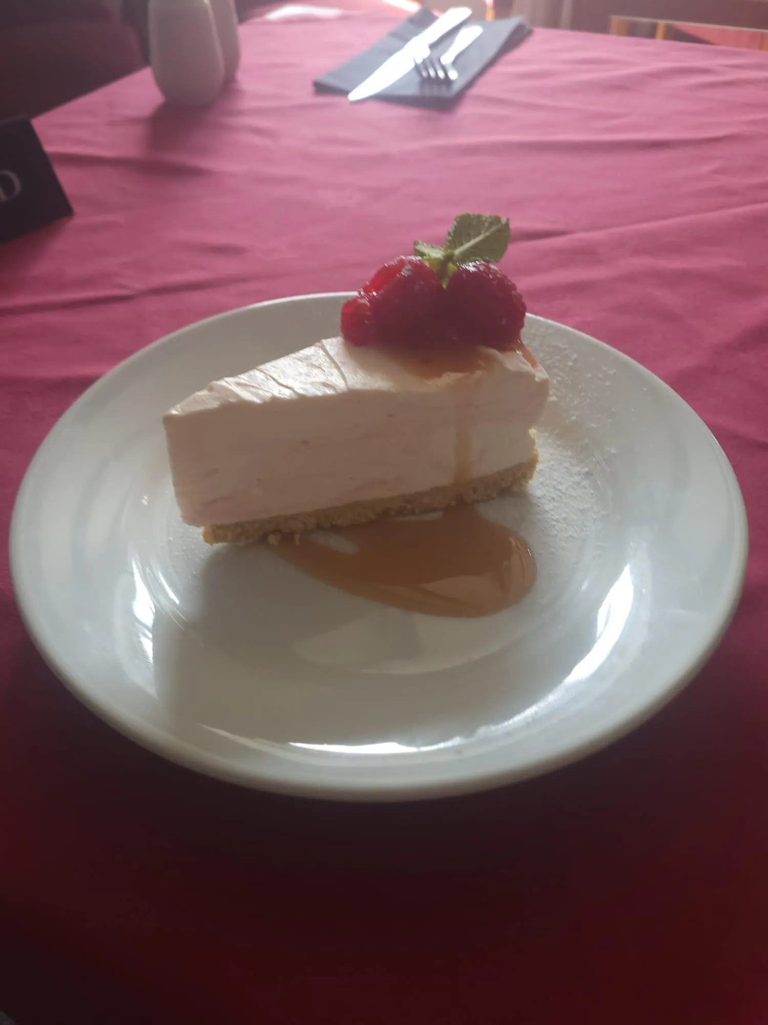 A piece of raspberry cheesecake and coulis.