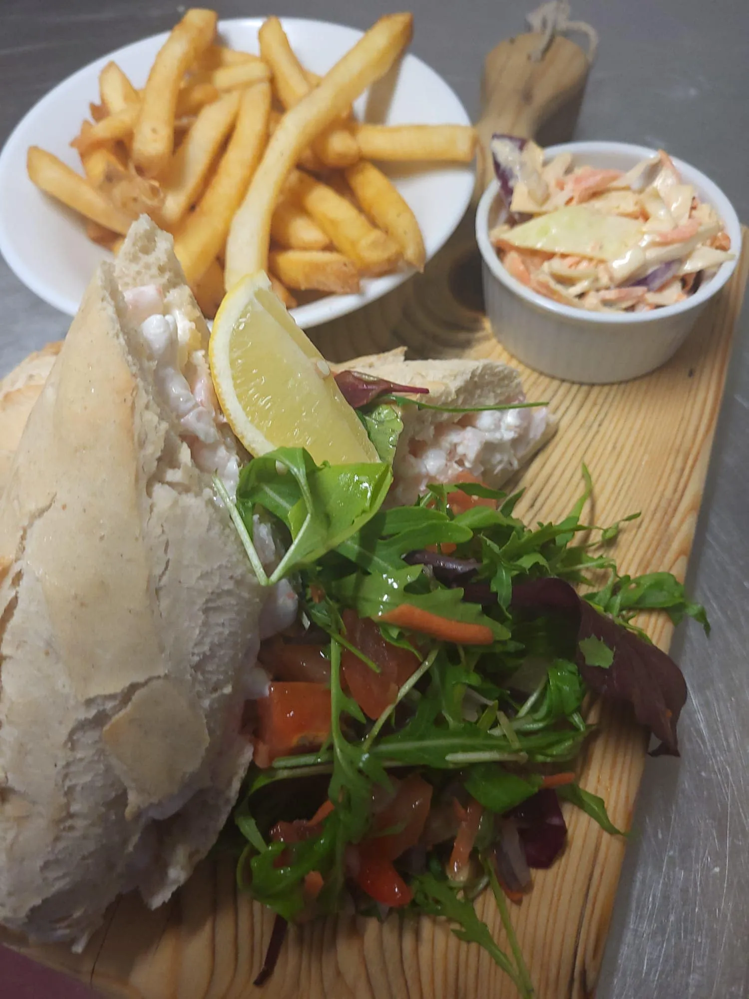A sandwich, chips, coleslaw and side salad.