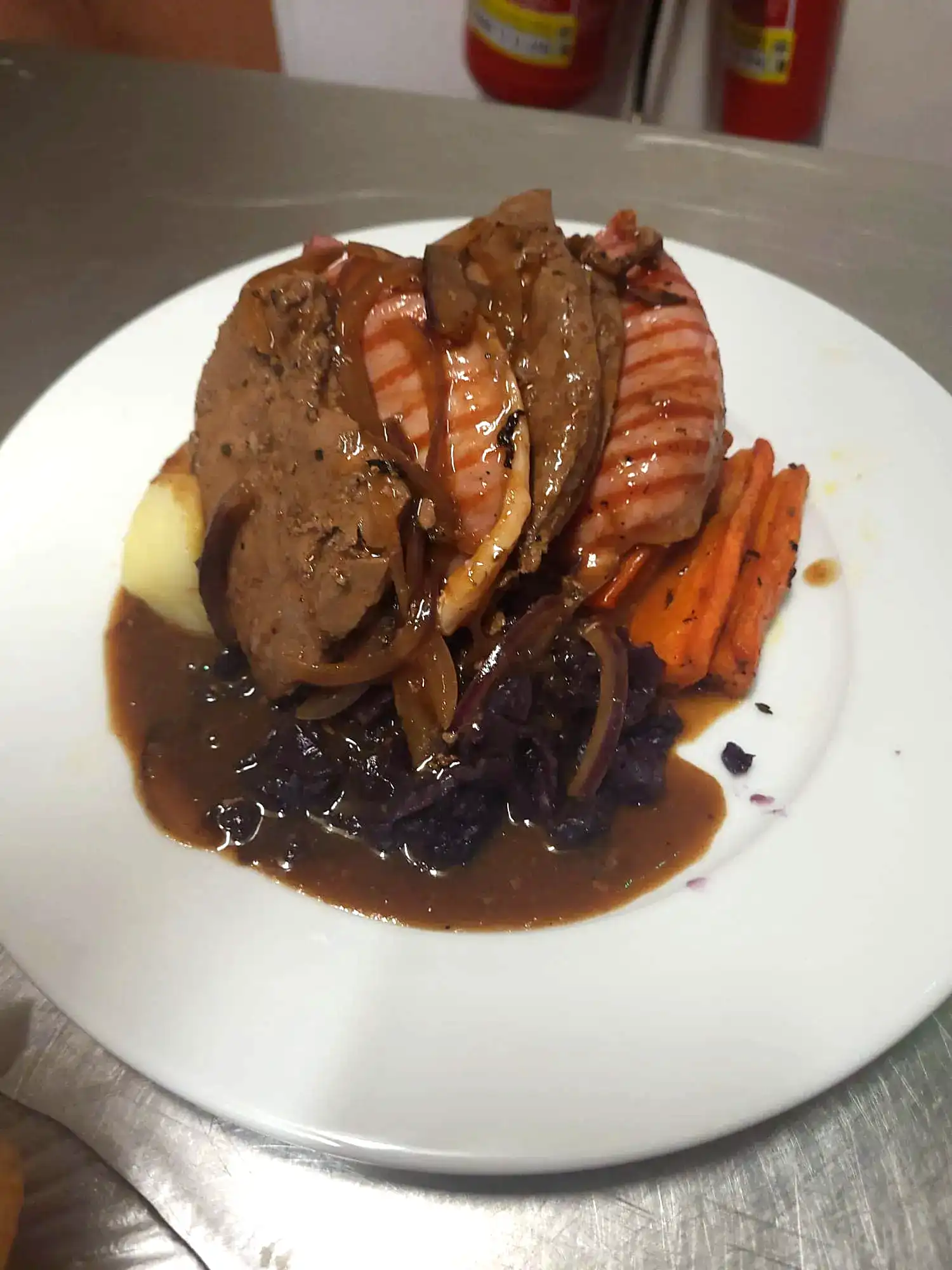 A white plate topped with meat, gravy and vegetables.