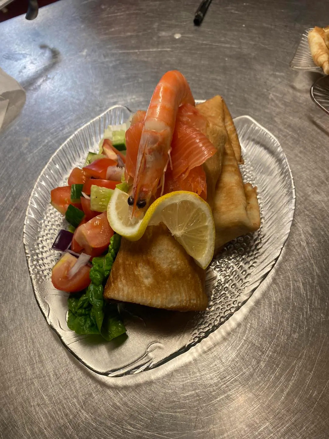 A plate of salmon with salad on a shiny table.