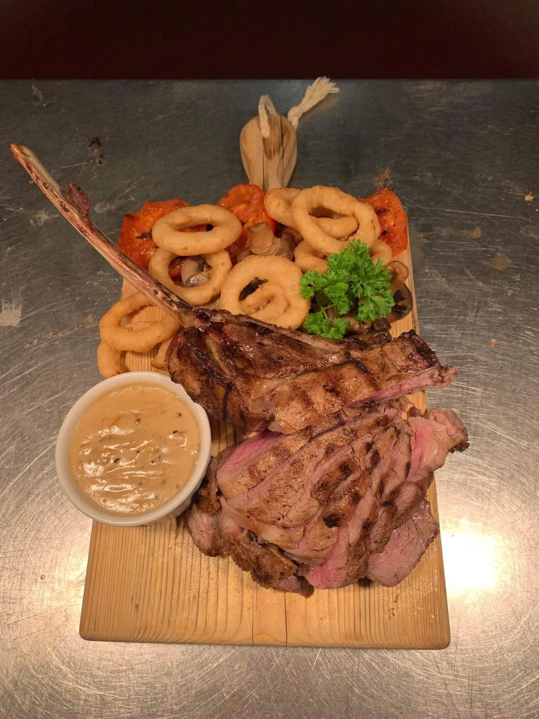 Steak and onion rings on a wooden board.