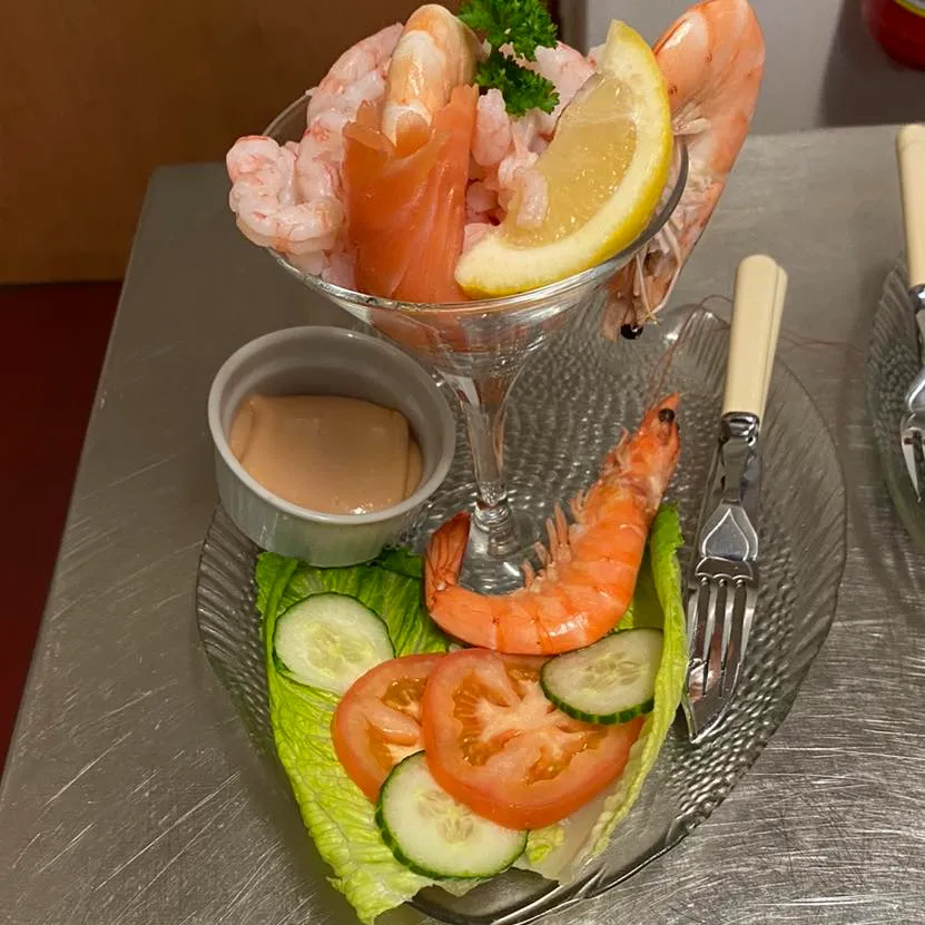 A plate of food that includes prawns, lettuce, tomato and cucumber.
