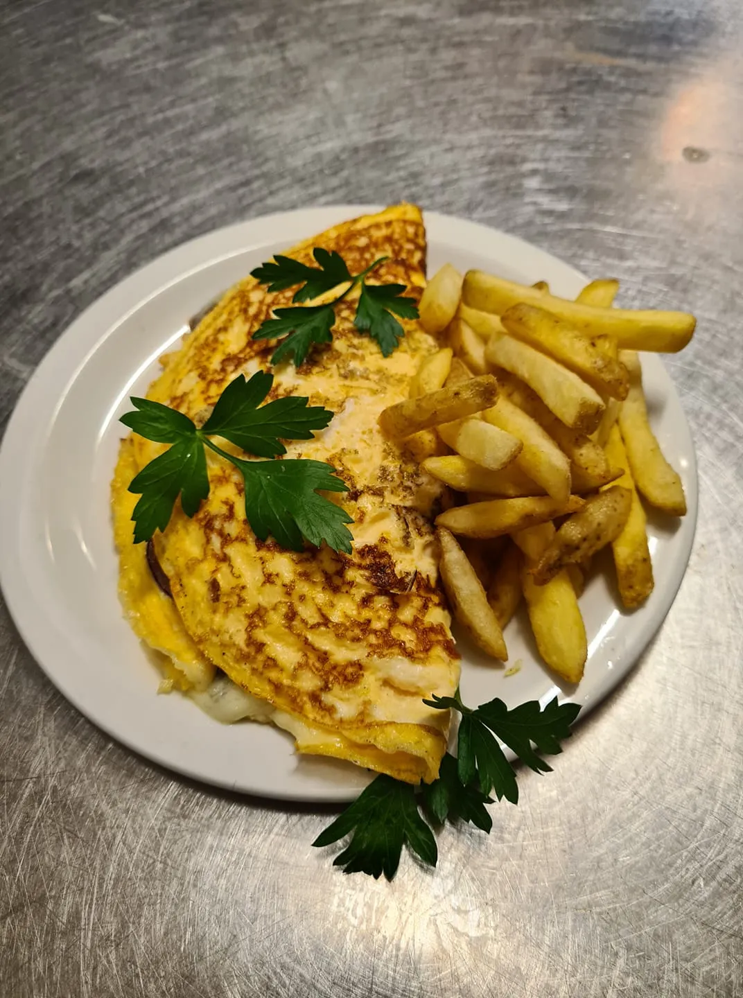 A white plate topped with chips and an omlette.