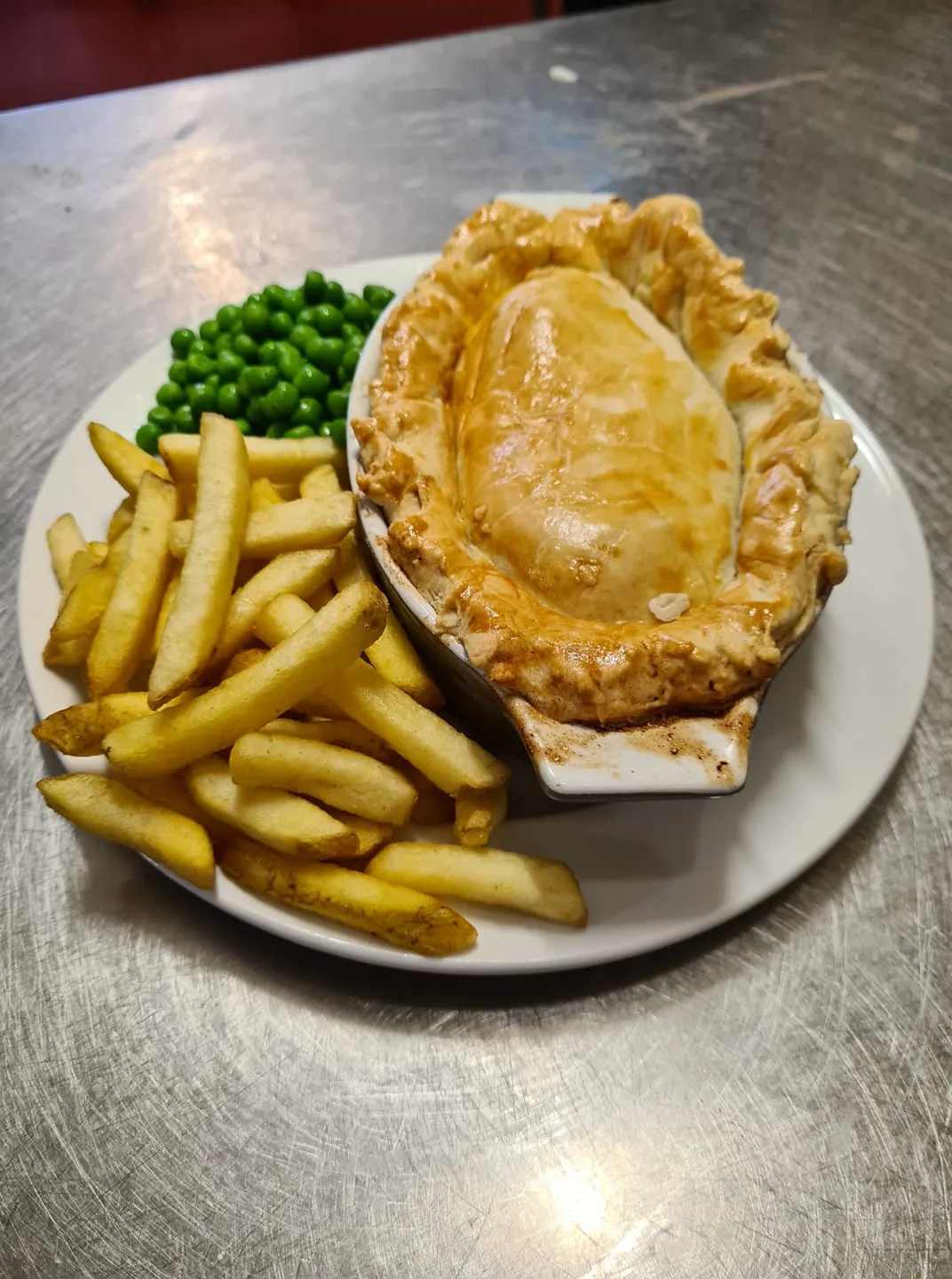 A white plate topped with a pie chips and peas.
