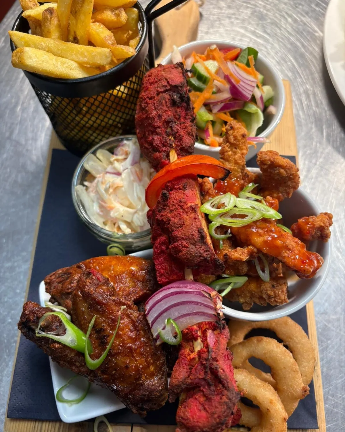 A plate of food that includes meat, onion rings, and coleslaw.